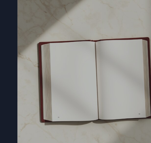 A beautifully bound book lying open on marble with two blank pages in the middle, the blank spread clearly deliberate, part of the book rather than damage to it.
